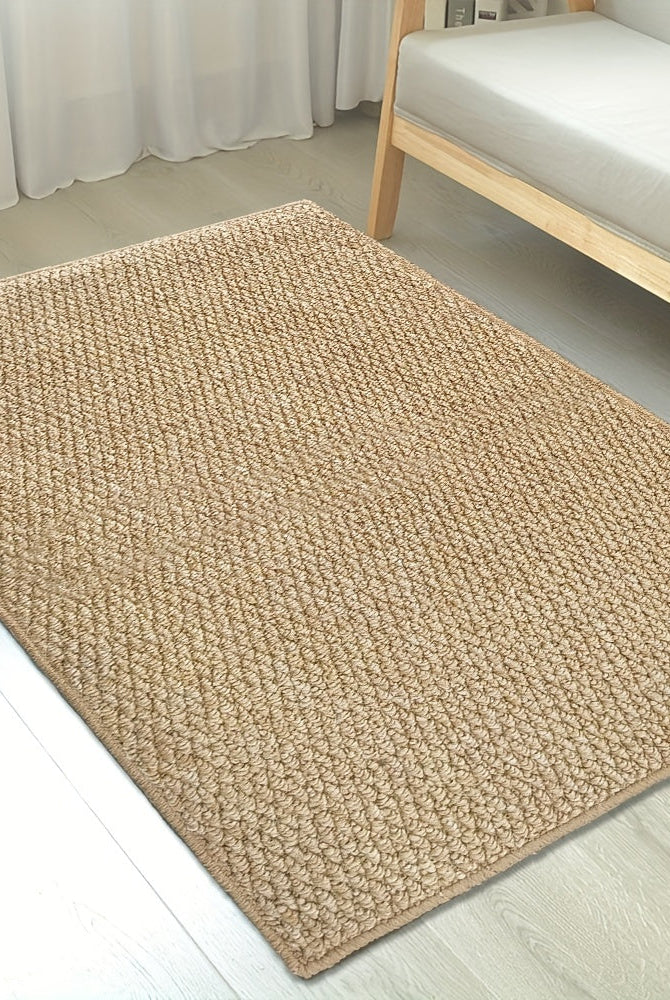 Beige woven rug on a light wooden floor with a chair in the background