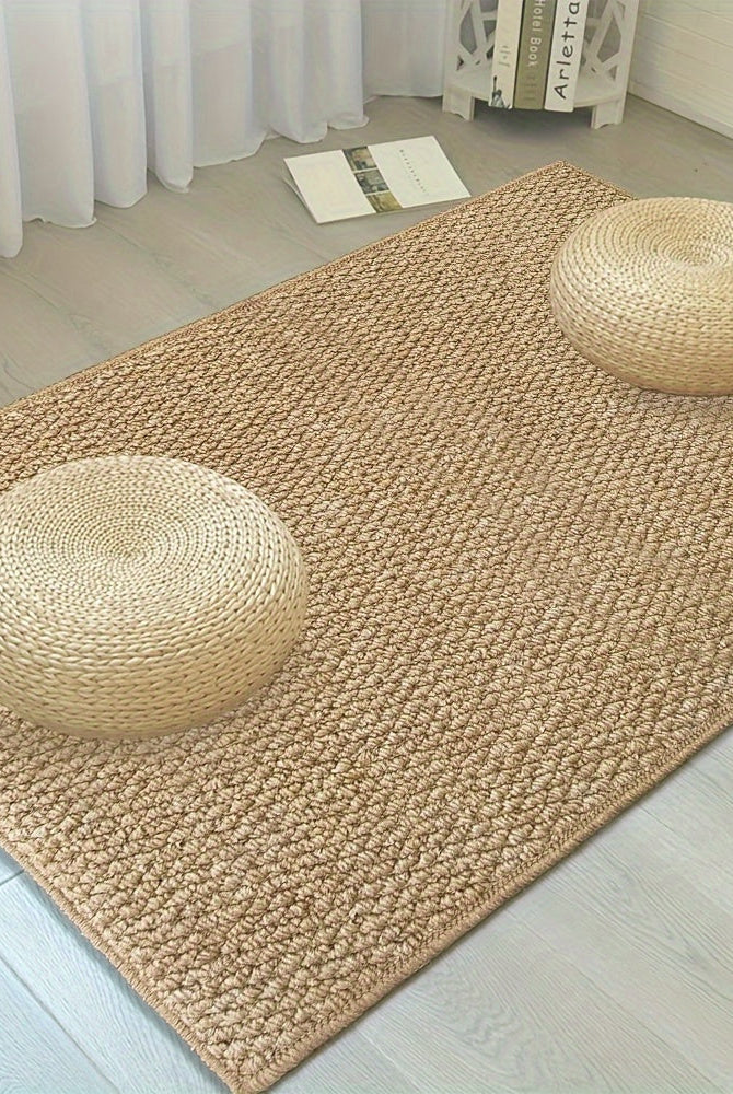 Beige woven rug with two round straw pillows on a light wooden floor.