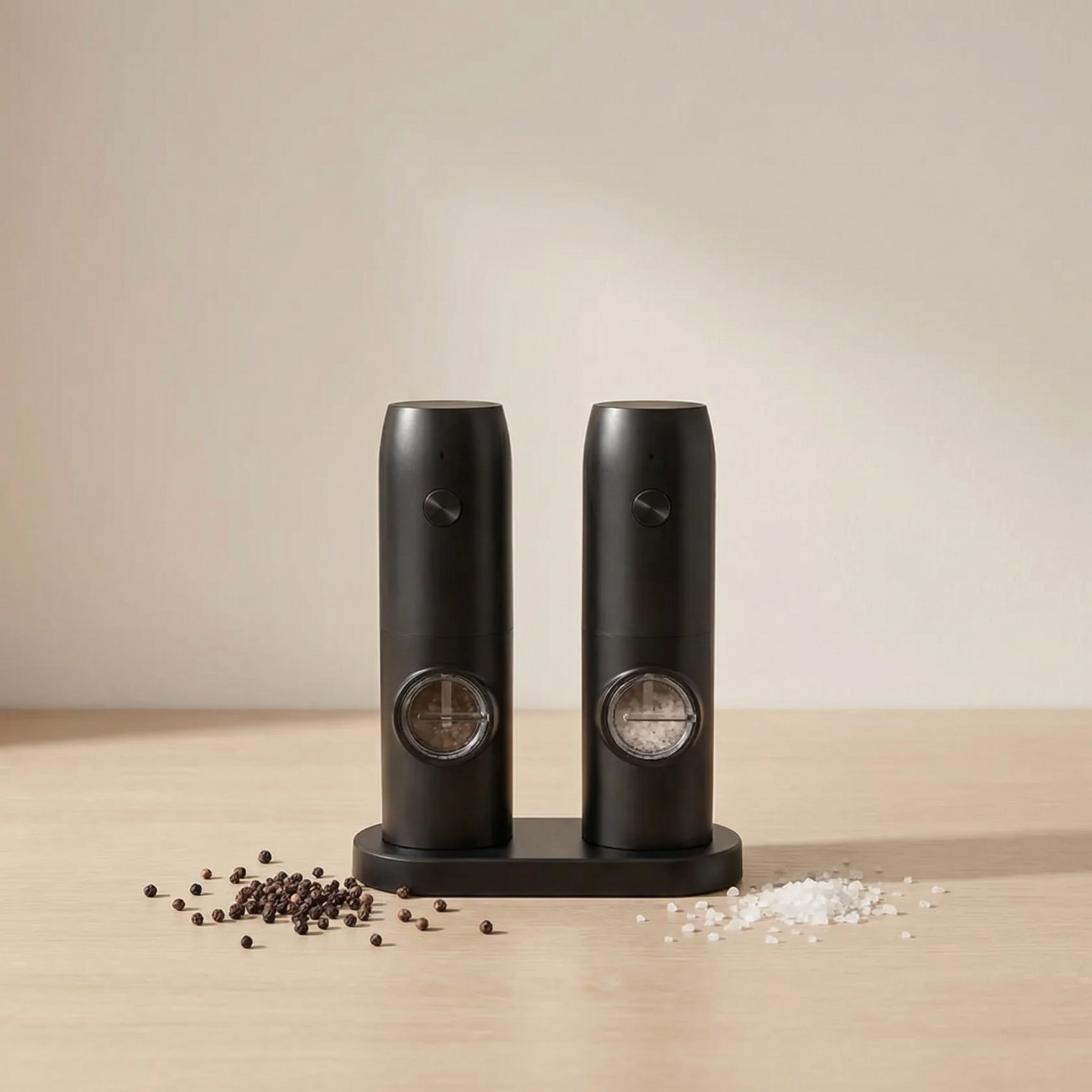 Black salt and pepper shakers on a beige surface with a neutral background