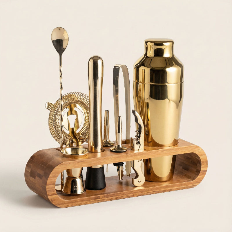 Set of gold cocktail tools on a wooden stand against a beige background