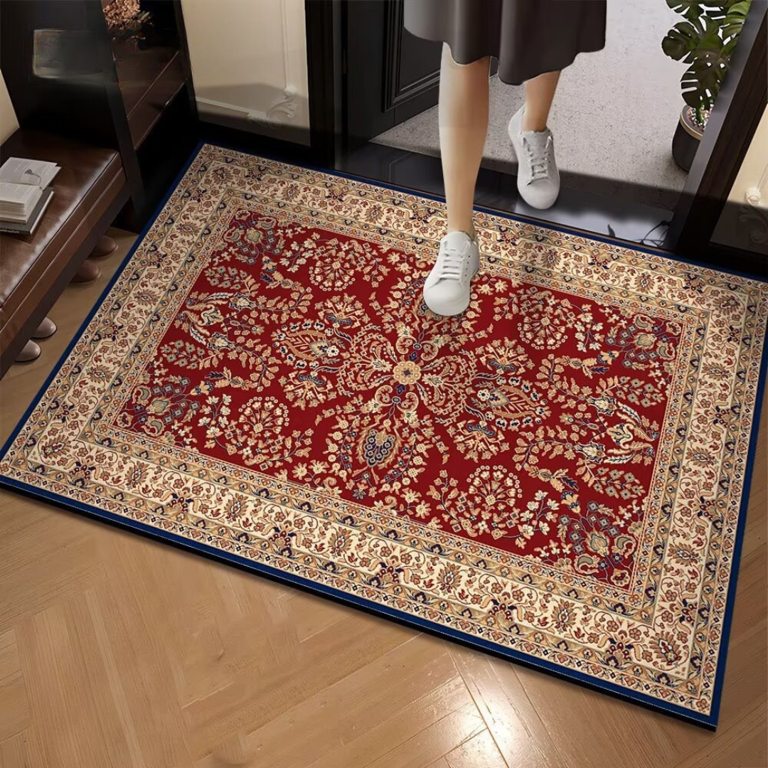 Decorative red and beige patterned rug on a wooden floor with a person stepping onto it.