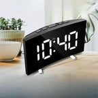 Digital clock on a table with plants in the background