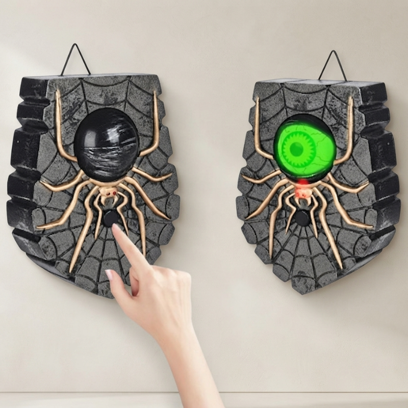 Two Halloween wall decorations shaped like stone spider caves hang on a beige wall. One has a black spider and eye, and the other has a glowing green spider and eye.