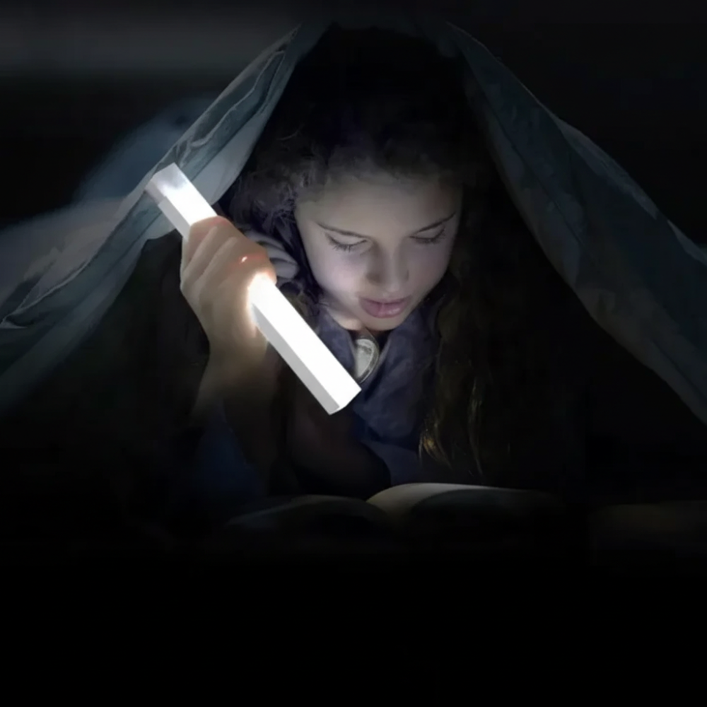 Person lying down in a dark setting, holding a light source.