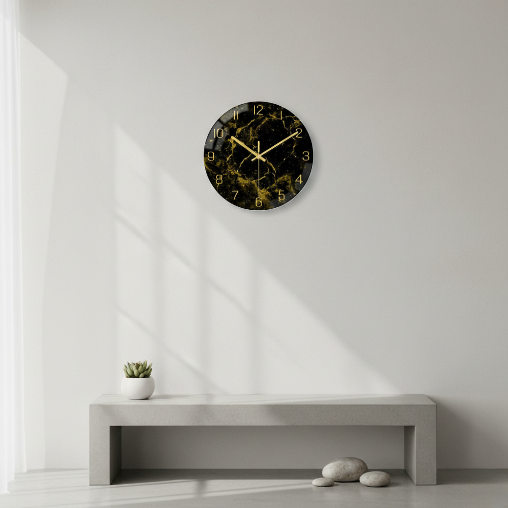 Black marble-patterned wall clock on a white wall with a concrete shelf below.