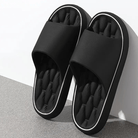 Black slippers with white trim on a gray surface