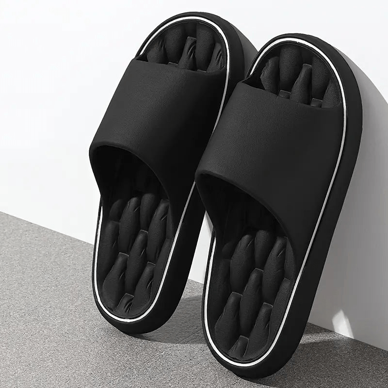 Black slippers with white trim on a gray surface