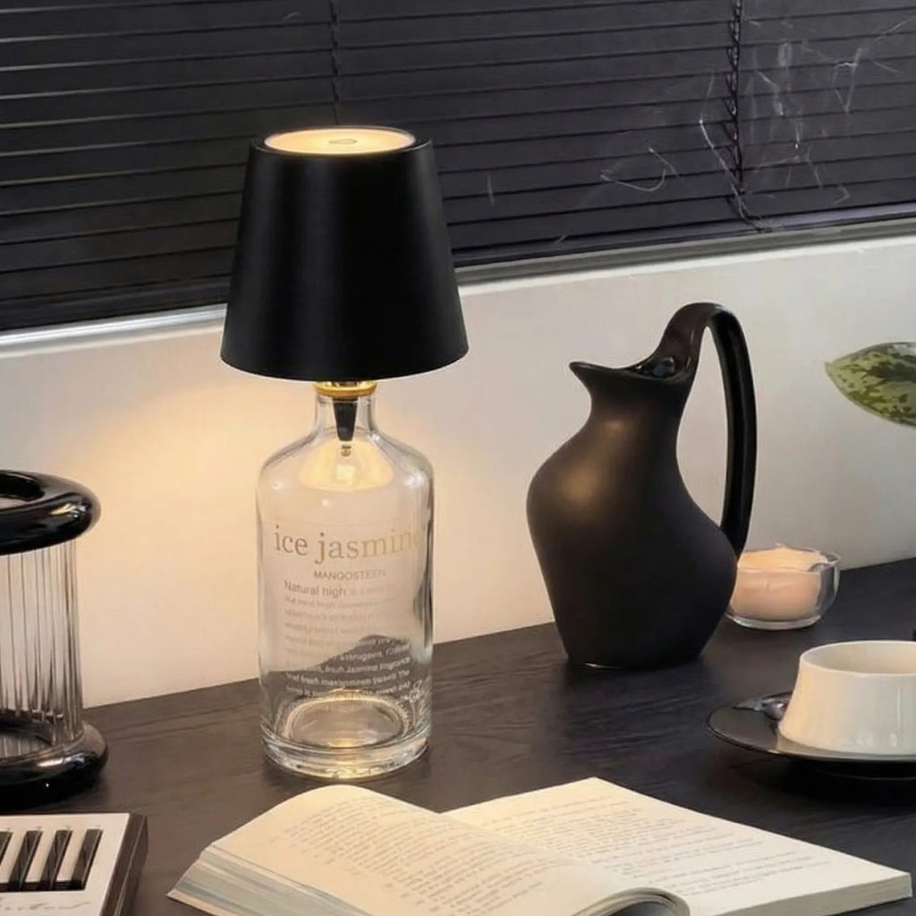Decorative setup with a lamp, book, and other items on a dark surface.