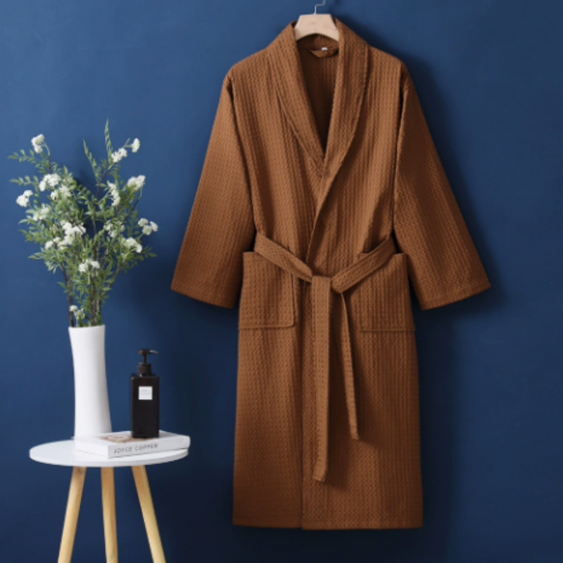 Brown robe hanging on a hook against a blue wall with a small table and decorative items.
