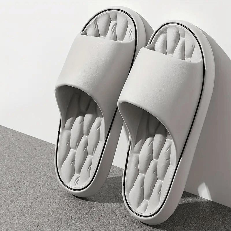 White slippers with quilted sole on a light gray background