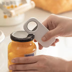 Person using a jar opener to open a jar with a blurred background