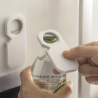 Person using a bottle opener on a clear bottle with a white background