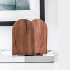 Two wooden bookends on a white surface with a blurred background