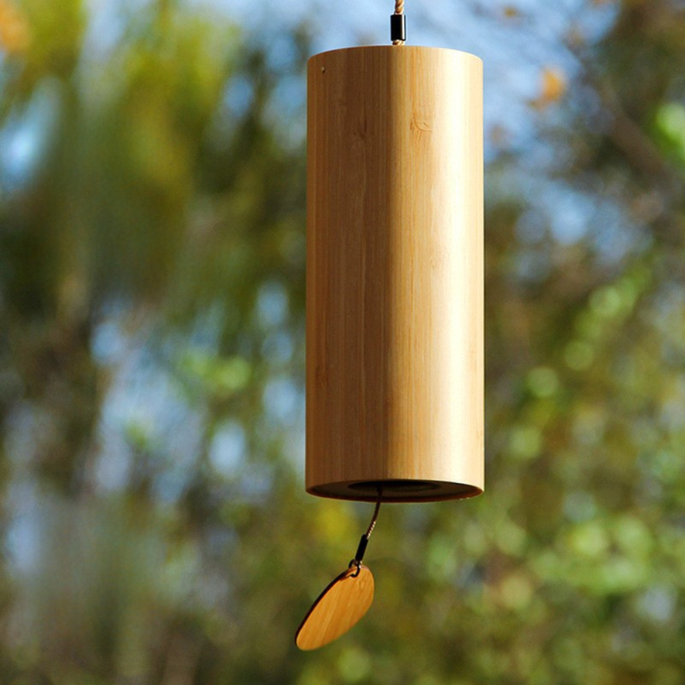 Wooden wind chime with a yellow feather against a blurred natural background