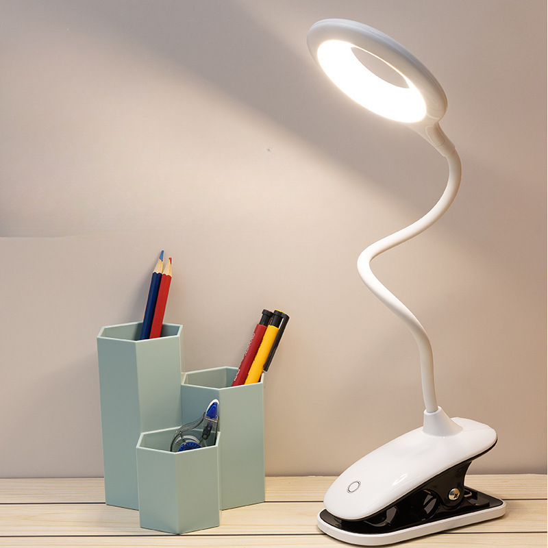 White LED desk lamp with flexible neck on a wooden surface, next to a pen holder with stationery items.