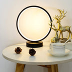 Round table with a lamp, cup, saucer, and decorative items on a neutral background