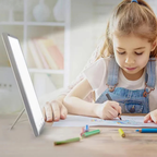 Child drawing at a desk with a lightbox and colored pencils.