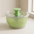 Green salad spinner on a light surface with a neutral background