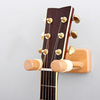 Guitar headstock attached to a wooden guitar wall hanger on a gray background