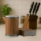 Wooden kitchen container with metallic lid on a countertop, with a knife block in the background.