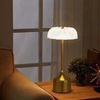 Gold table lamp with a textured white shade on a wooden surface, soft lighting.