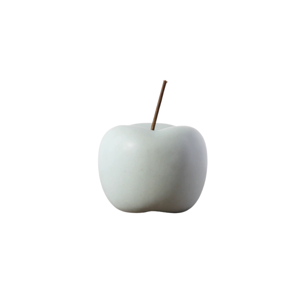 White ceramic apple with a brown stem on a white background