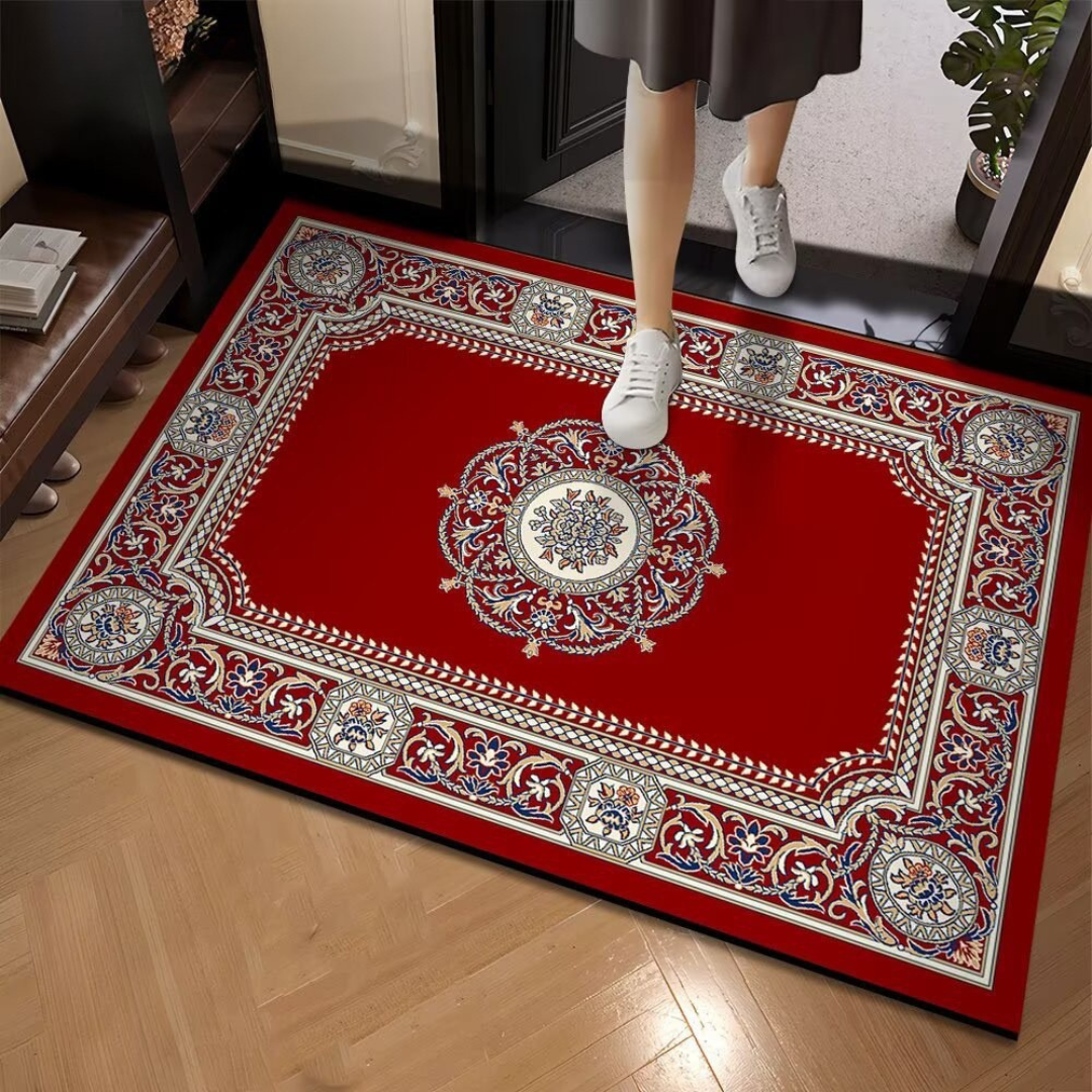 Decorative red rug with intricate patterns on a wooden floor, person stepping onto it.