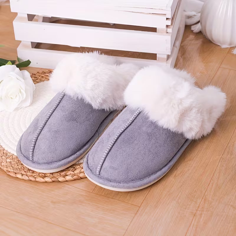 Gray slippers with white fur trim on a wooden floor.