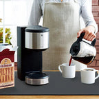 Person pouring coffee from a carafe into a cup next to a coffee maker and a bag of Colombian coffee beans.