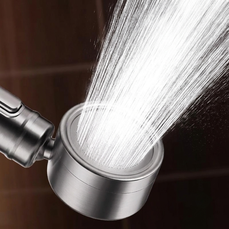 Metallic shower head with water spraying out against a dark background