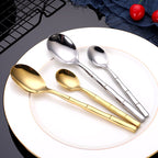 Set of gold and silver spoons on a white plate with a dark background