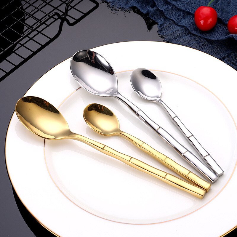 Set of gold and silver spoons on a white plate with a dark background