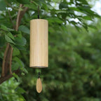 Wooden wind chime hanging among green leaves