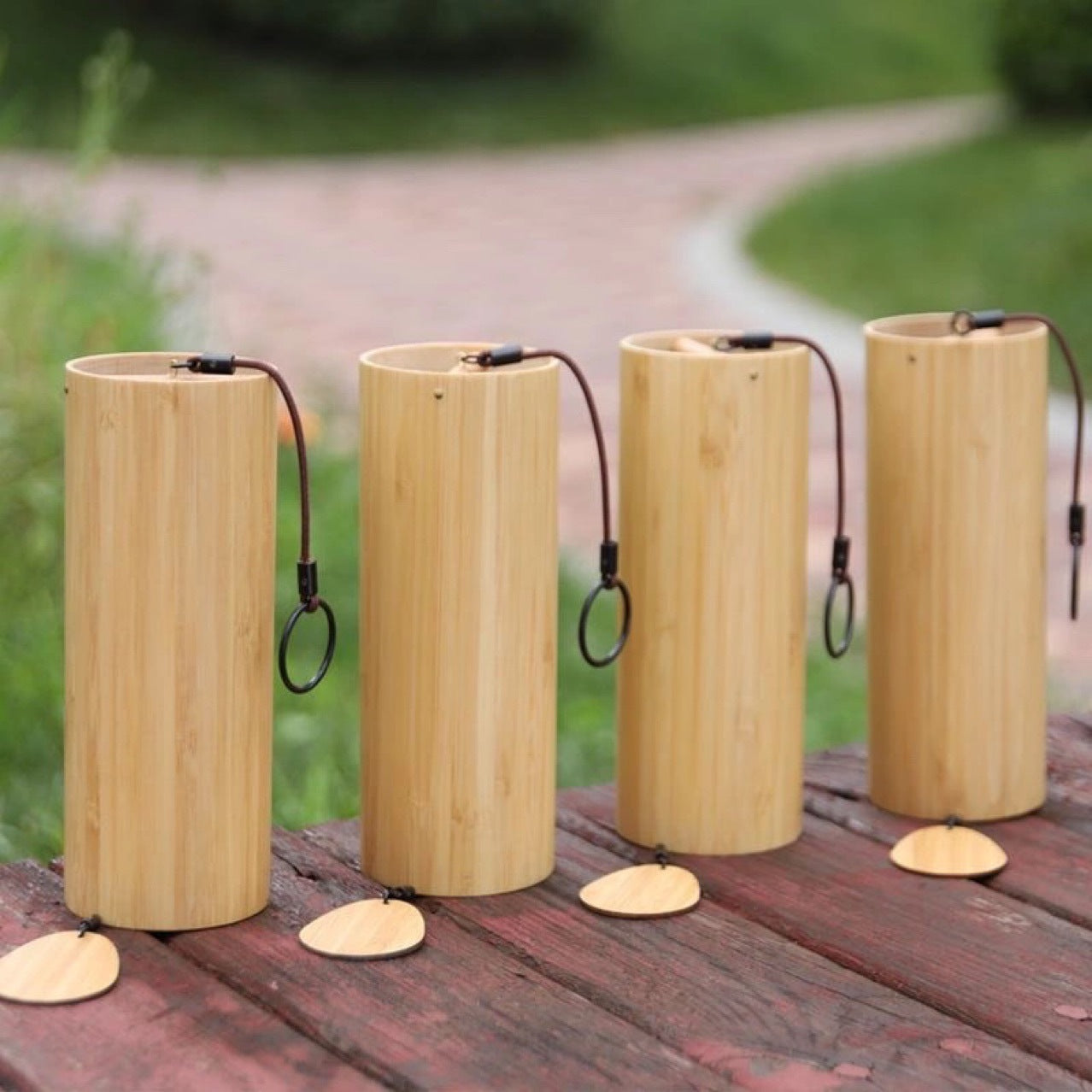 Four cylindrical wooden bird feeders on a wooden surface with a blurred natural background