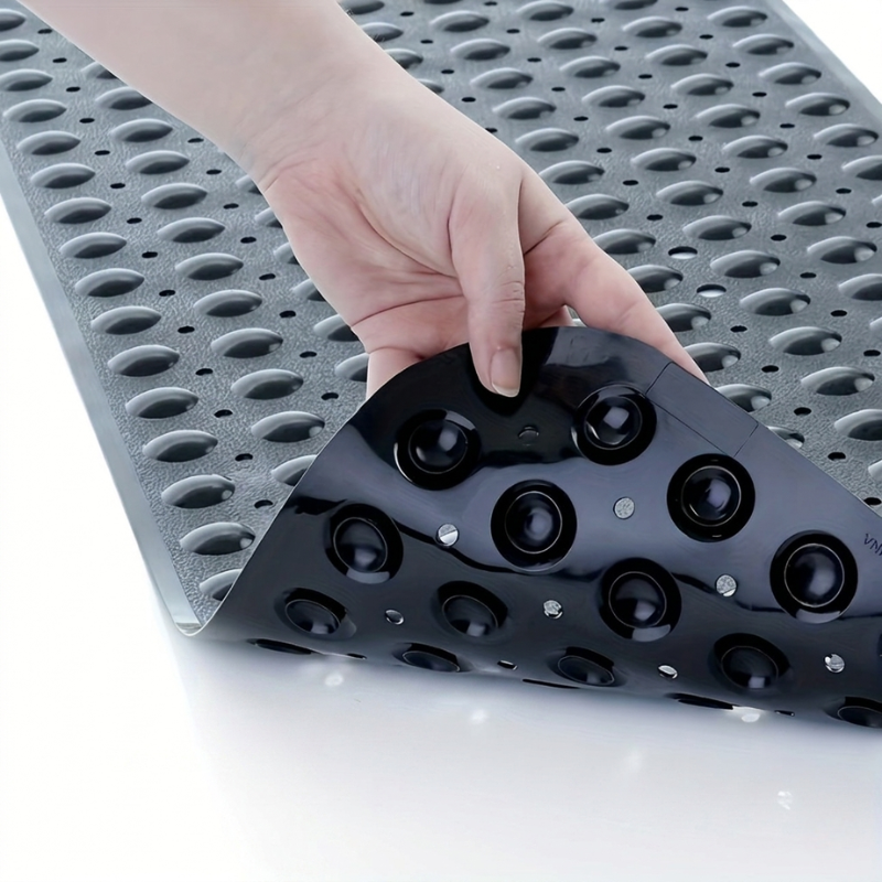 Hand holding a black textured object against a gray perforated background