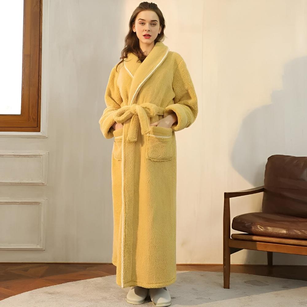 Woman wearing a yellow robe standing in a room with a brown chair and white walls.