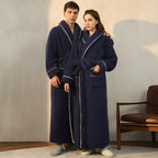 Two people wearing navy blue robes with white trim in a room.
