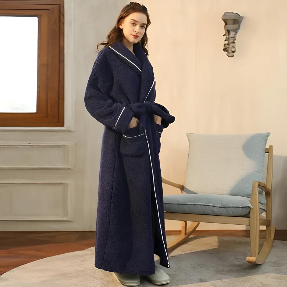 Woman wearing a long navy blue robe in a room with a rocking chair and window.