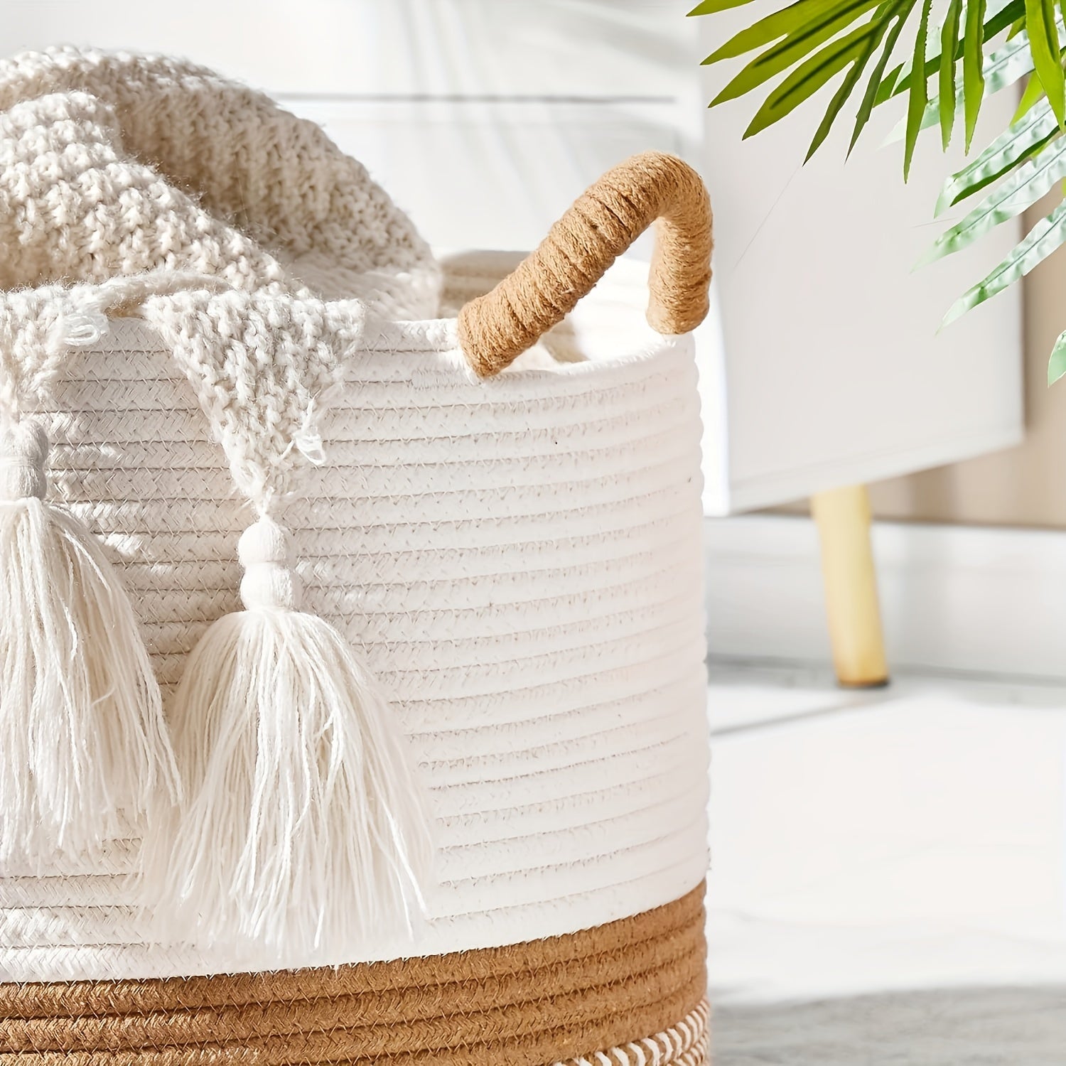 Woven basket with natural handle and tassels on a blurred indoor background