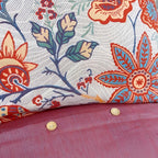 Close-up of floral fabric with red, blue, and green colors on a pink background.
