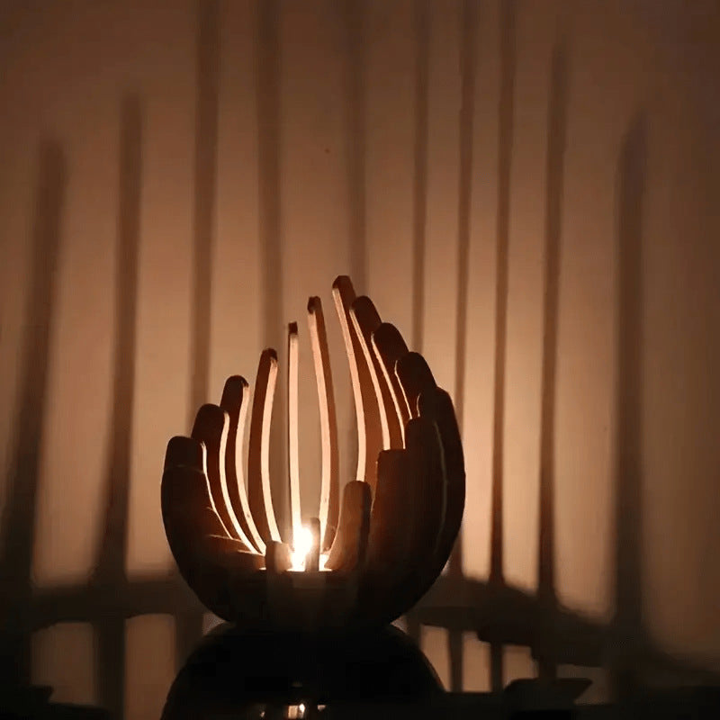 Candle holder with a candle inside, casting shadows on a wall.