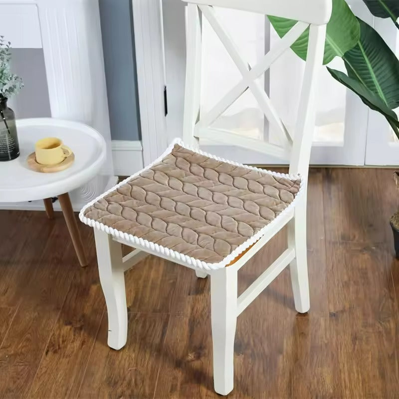 Brown textured chair pad on a white chair in a room with a table and plants.