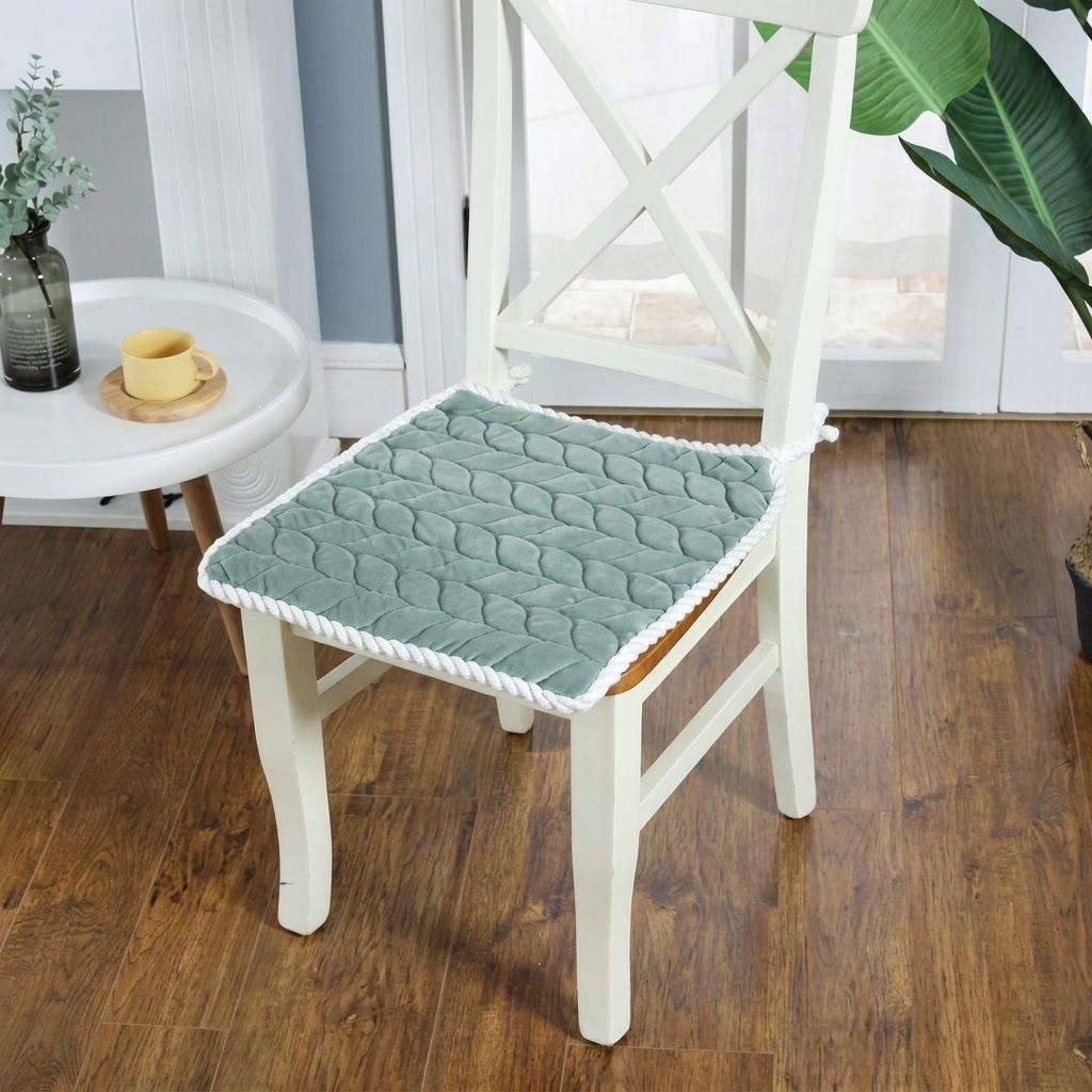 Green textured chair pad on a white chair in a room with wooden floor and window.