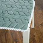 Green quilted chair cover on a wooden chair with a blurred background