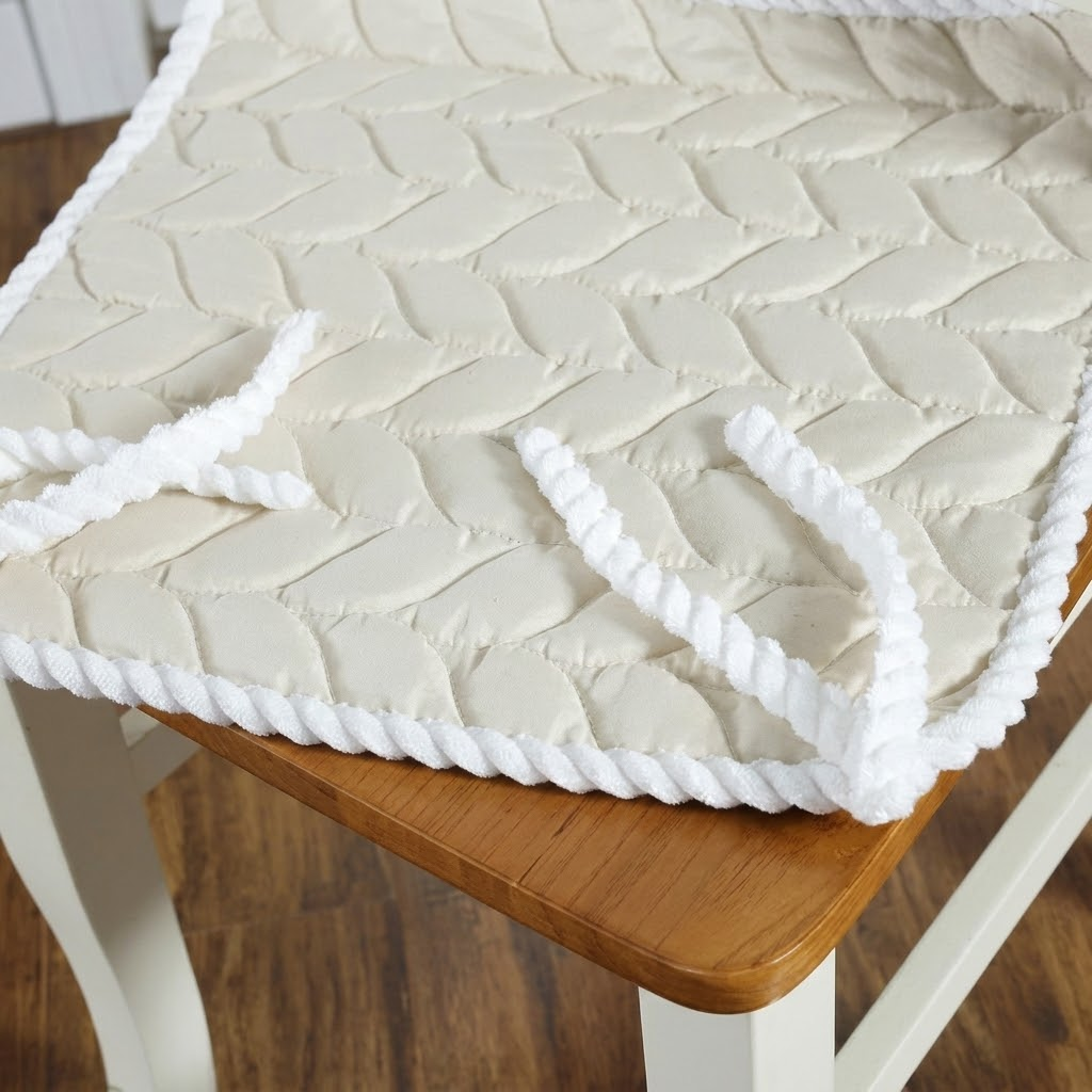 Beige textured chair pad with white trim on a wooden chair.