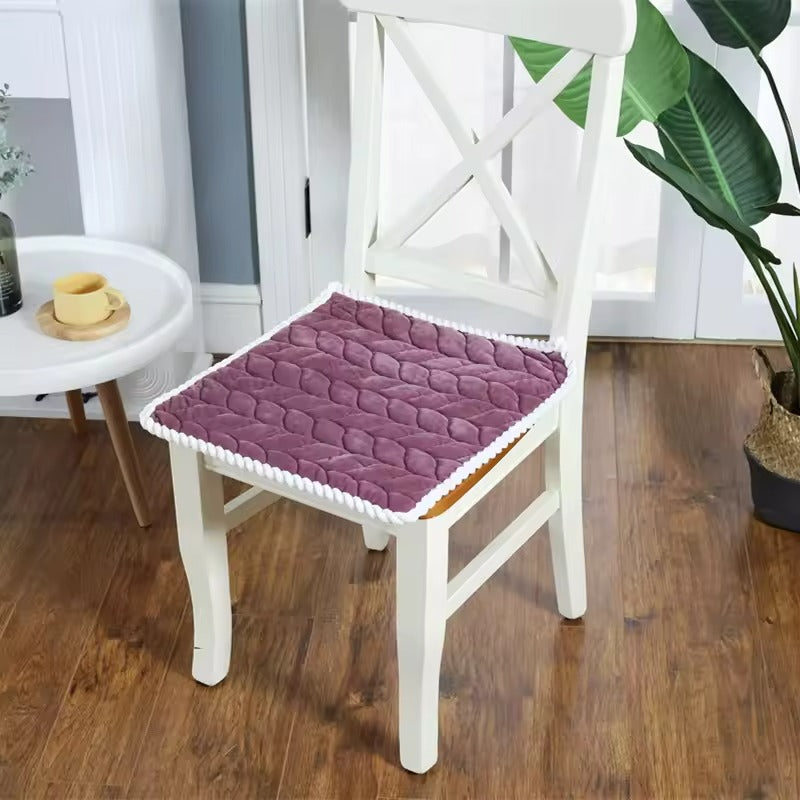 Purple quilted chair pad on a white chair in a room with wooden floor and plants.