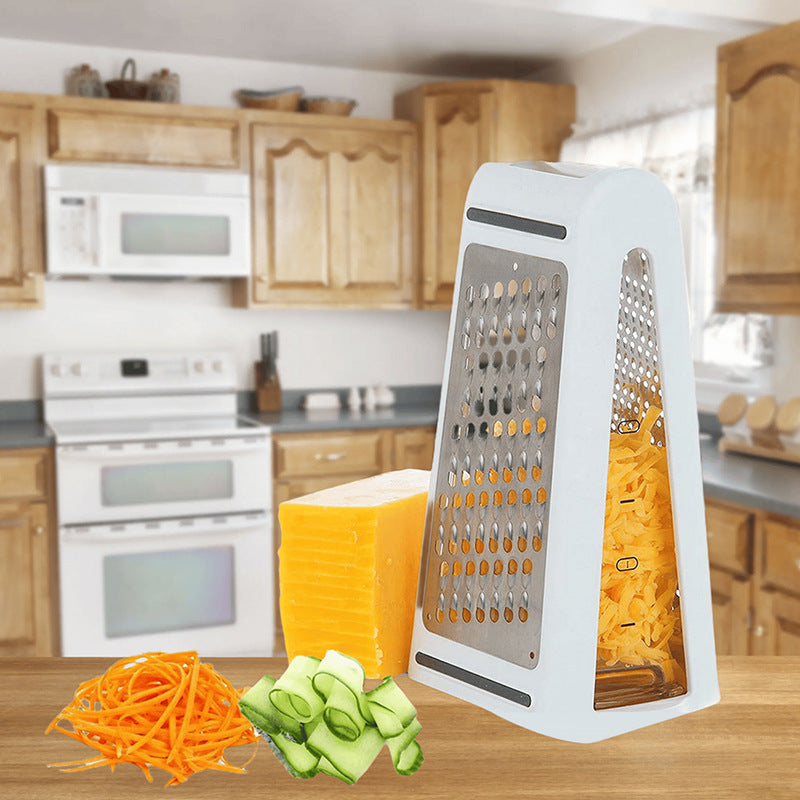 Box grater with shredded carrots and zucchini on a kitchen counter