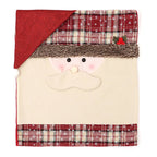 A festive Christmas-themed blanket or towel featuring a Santa Claus face design. The product has a cream-colored body, a red faux-fur trim, a red and beige plaid pattern with white snowflakes, and a red triangular top section.