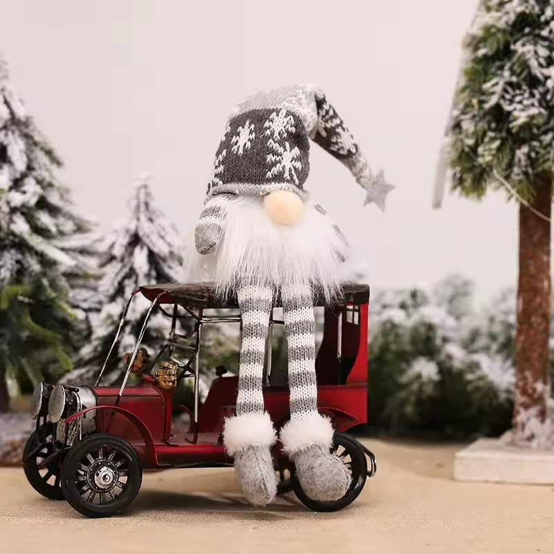 Gnome figurine with a striped hat and scarf sitting on a small red car in a snowy landscape.