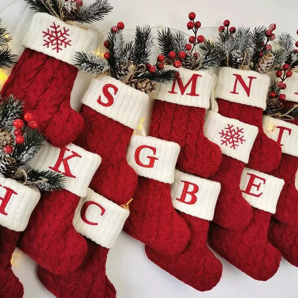 Red Christmas stockings with lettered tops on a white background